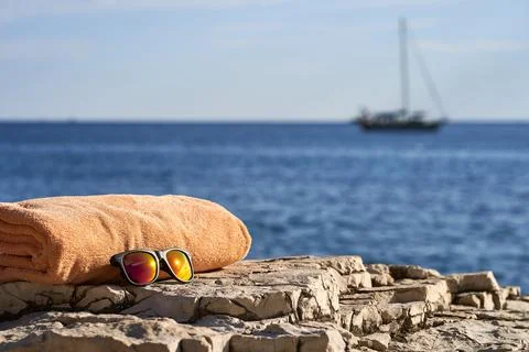 Black e-reader, orange towel and sunglasses laying on a rock near to Istrian sea Stock Photos