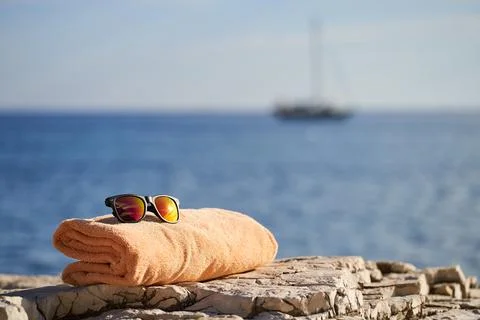 Black e-reader, orange towel and sunglasses laying on a rock near to Istrian sea Stock Photos