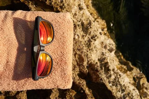 Black e-reader, orange towel and sunglasses laying on a rock near to Istrian sea Stock Photos
