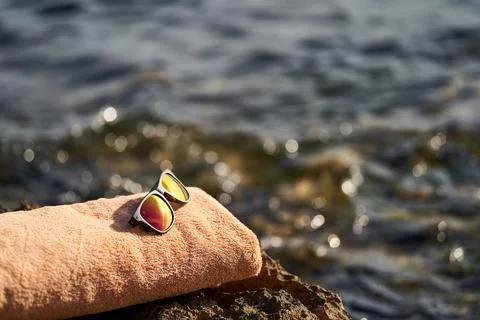 Black e-reader, orange towel and sunglasses laying on a rock near to Istrian sea Stock Photos