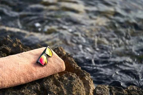 Black e-reader, orange towel and sunglasses laying on a rock near to Istrian sea Stock Photos