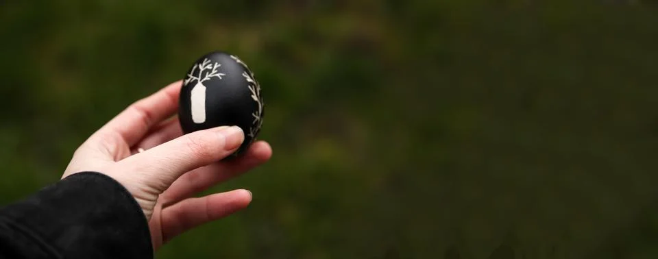 Black Easter egg in hand. Easter banner background. Defocus, blu Foto stock