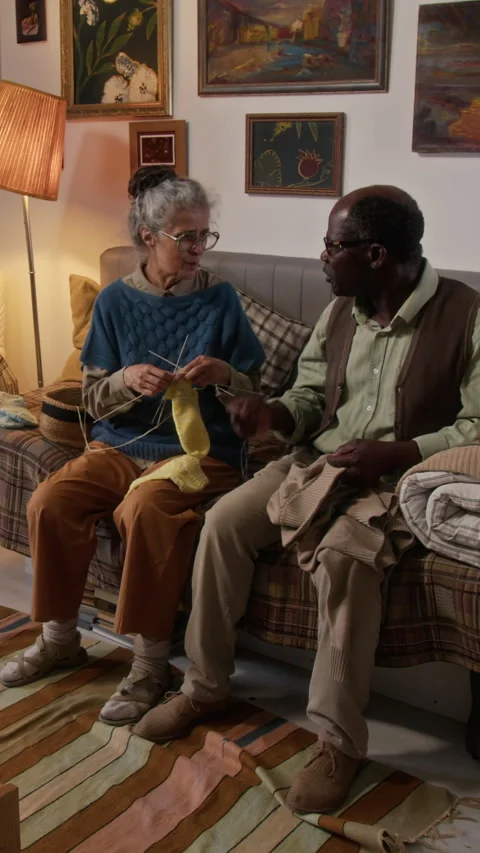 Black Elderly Man Mending his Jacket and Chatting with his Knitting Wife Video stock 314622404