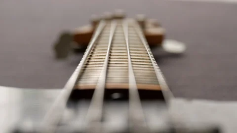 Black electric bass. FOCUS PULL of instrument laying flat on a grey Stock Footage 104653796