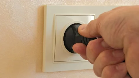 A black electric plug with a wire is pulled out from a white socket by hand. Stock Footage 213631969