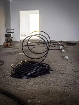 Black electrical conduit coils inside unfinished building Stock Photos