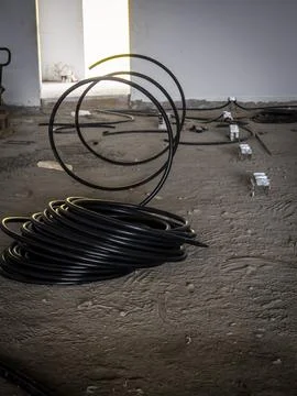 Black electrical conduit coils inside unfinished building Stock Photos