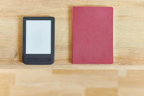 Black electronic book with empty screen and red notepad on wooden table top v Stock Photos