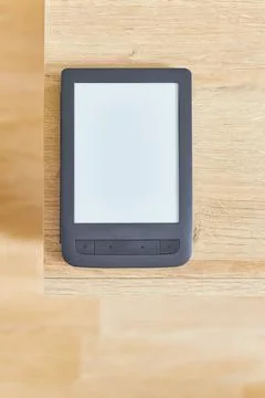 Black electronic book with empty screen on wooden table and free space for ad Stock Photos