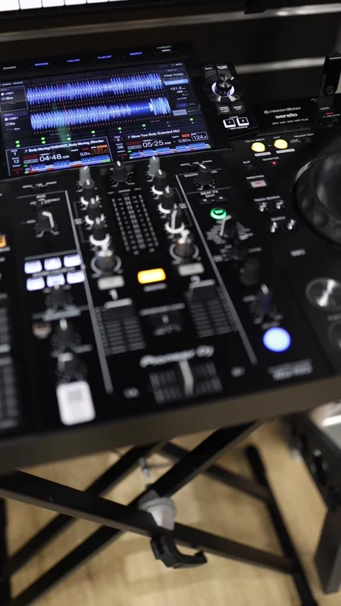 A black electronic device with a keyboard and a screen. The device is a DJ mixer Stock Footage 294702581
