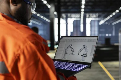Black employee using automation software connected to robot machinery Stockfoto's