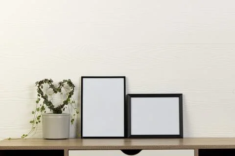 Black empty frames with copy space and heart shape plant on table against white Stock Photos