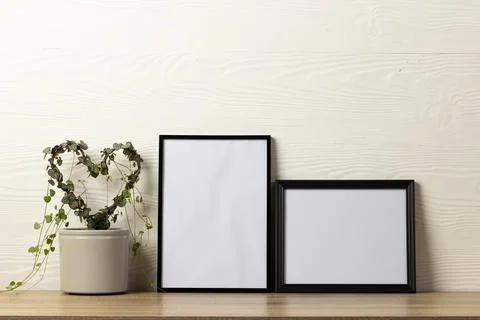 Black empty frames with copy space and heart shape plant on table against white Stock Photos