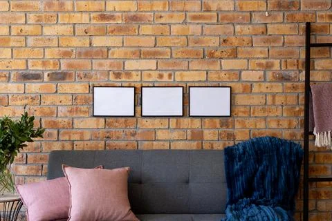 Black empty frames with copy space and plant against brick wall in room with Stock Photos