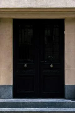 Black entrance door with bronze knobs in a classic style building Foto stock