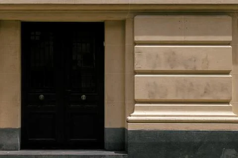Black entrance door with bronze knobs in a classic style building Stock Photos