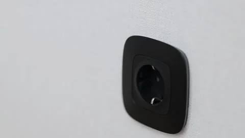 Black european plastic socket on white wallpaper. Black socket on a white wall. Stock Footage 235531292