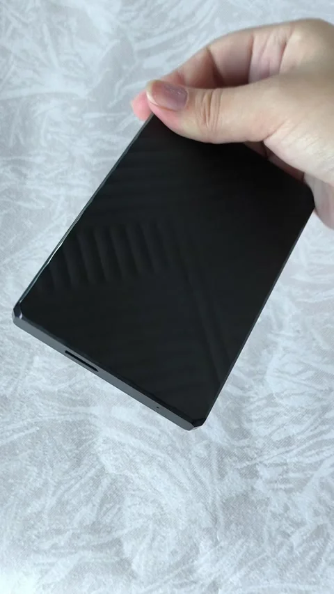A black external HDD hard drive in a womans hand. Additional memory card for PC Stock Footage 313980358