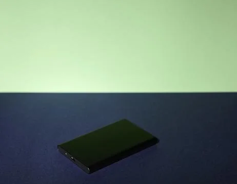 Black external SSD on gradient green and blue background with minimal compo.. Stockfoto's