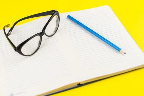 Black eye glasses and notepad planner with pencil on yellow background. Flat  Stock Photos