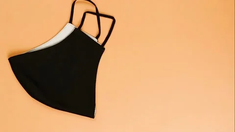 Black face protective reusable mask appear and go out on orange background. Vídeo Stock 131933330