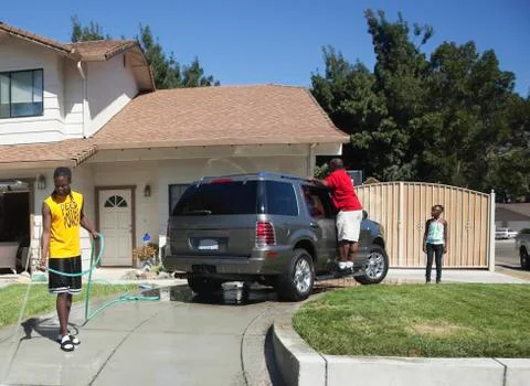 Black family washing car in driveway Stock Photos