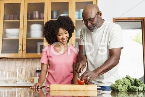 Black Father And Daughter Chopping Tomato In Kitchen