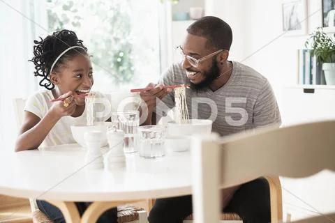 Black Father And Daughter Eating Noodles
