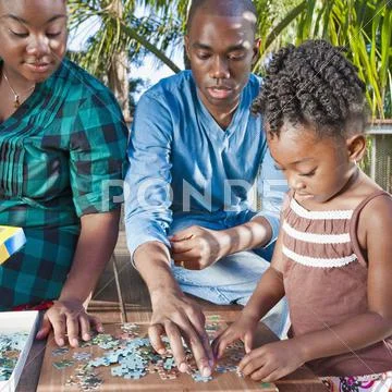 Black Father And Mother Solving Puzzle With Child