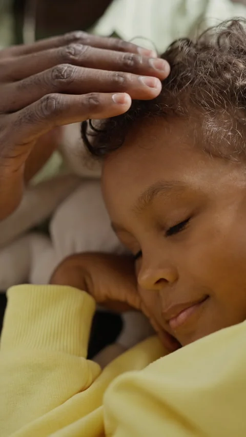 Black Father Gently Stroking Forehead of Sleeping Son at Home Stock Footage 345492932