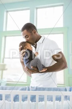 Black Father Kissing Baby Son On Forehead