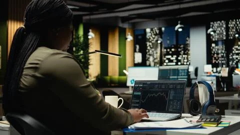 Black female administrator analyzes data on stock and forex trading Stock Photos