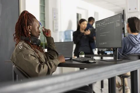 Black female developer touching forehead with pen in tech office 스톡 사진