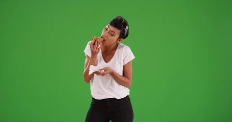 Black female eating a slice of delicious cheese pizza for lunch on green screen Stock Footage