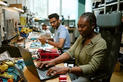 Black Female Engineer Programming Robotics on Laptop in Workshop Stock Photos