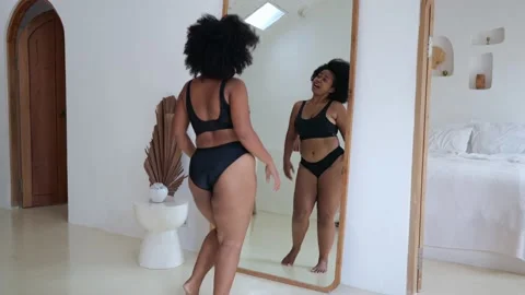 A black female plus size model dances at home in front of a mirror in black Video stock 205587595