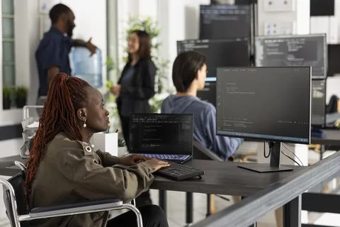 Black female programmer in wheelchair coding on computer Foto stock