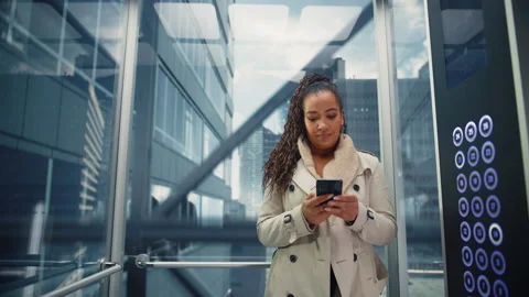 Black Female Riding Elevator to Office Using Smartphone Stock Footage 167833116