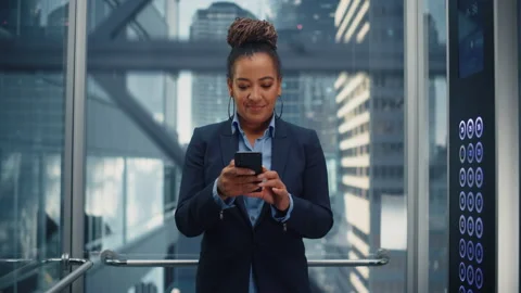 Black Female Riding Elevator to Office Using Smartphone Stock Footage 167839859