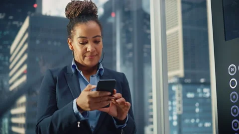 Black Female Riding Elevator to Office Using Smartphone Stock Footage 167839887