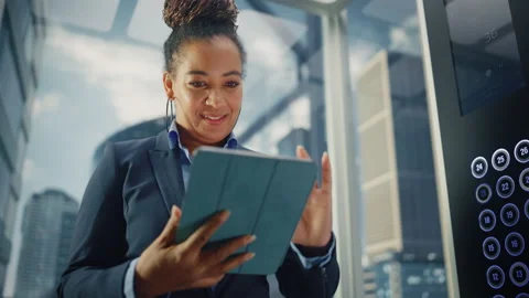 Black Female Riding Elevator to Office Using Tablet Stock Footage 167840491