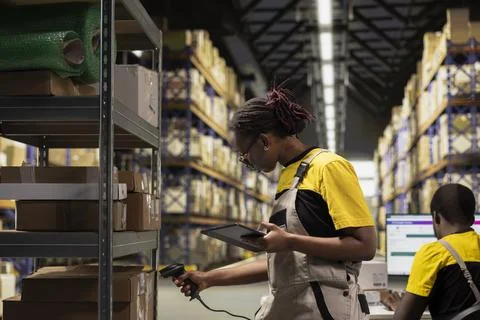 Black female staff using scanner checking airway bill numbers in inventory 库存照片