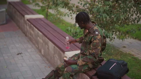Black Field Medic Pausing At Dusk, Camouflage Uniform, Empty Bench Beside, Small Stock Footage 327228796