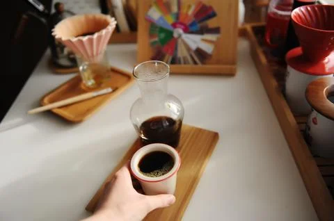 Black filter coffee in ceramic cup in hand. Bamboo board. Glass decanter. Third Stock Photos