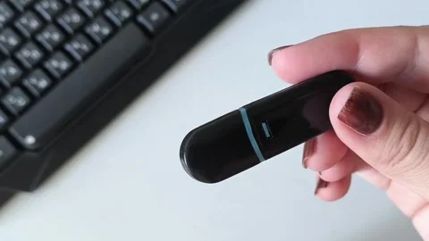 A black flash drive in a womans hand against the background of a keyboard. Data Stock Footage 320523516