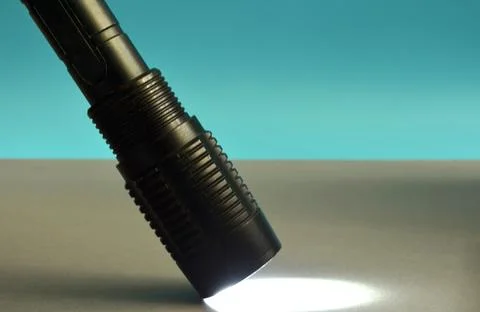 A black flashlight shines on a gray background. Stock Photos