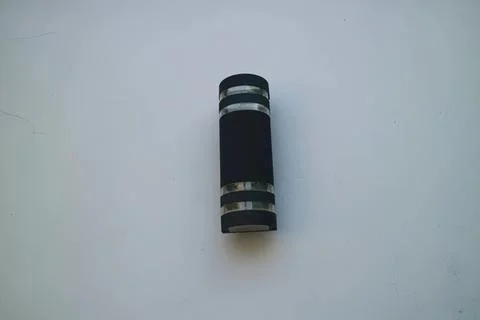 Black flashlight with silver bands on a plain background Stock Photos