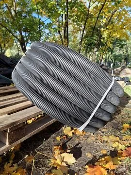 Black flexible plastic pipe is wound into a coil lies on construction site Stockfoto's