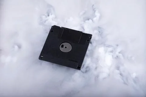 Black floppy disk in clouds. Conceptual image Stock Photos