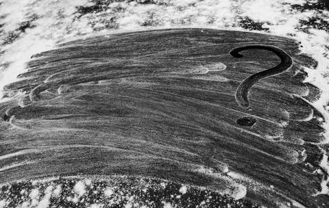 Black flour background. Close up of question mark on flour mixture Stock Photos